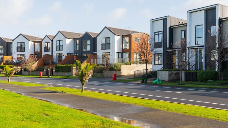 Row of designed and furnished townhouses next to a road in Auckland. 