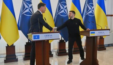 Die beiden stehen an Rednerpulten und schütteln sich die Hand. Dahinter mehrere Flaggen der Nato und der Ukraine.