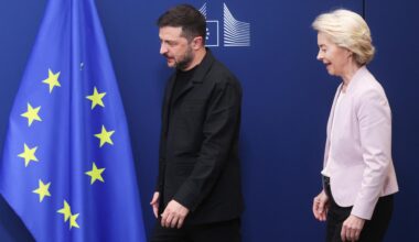 Der ukrainische Präsident Selenskyj und EU-Kommissionspräsidentin von der Leyen stehen vor einem blauen Hintergrund mit einer europäischen Flagge.