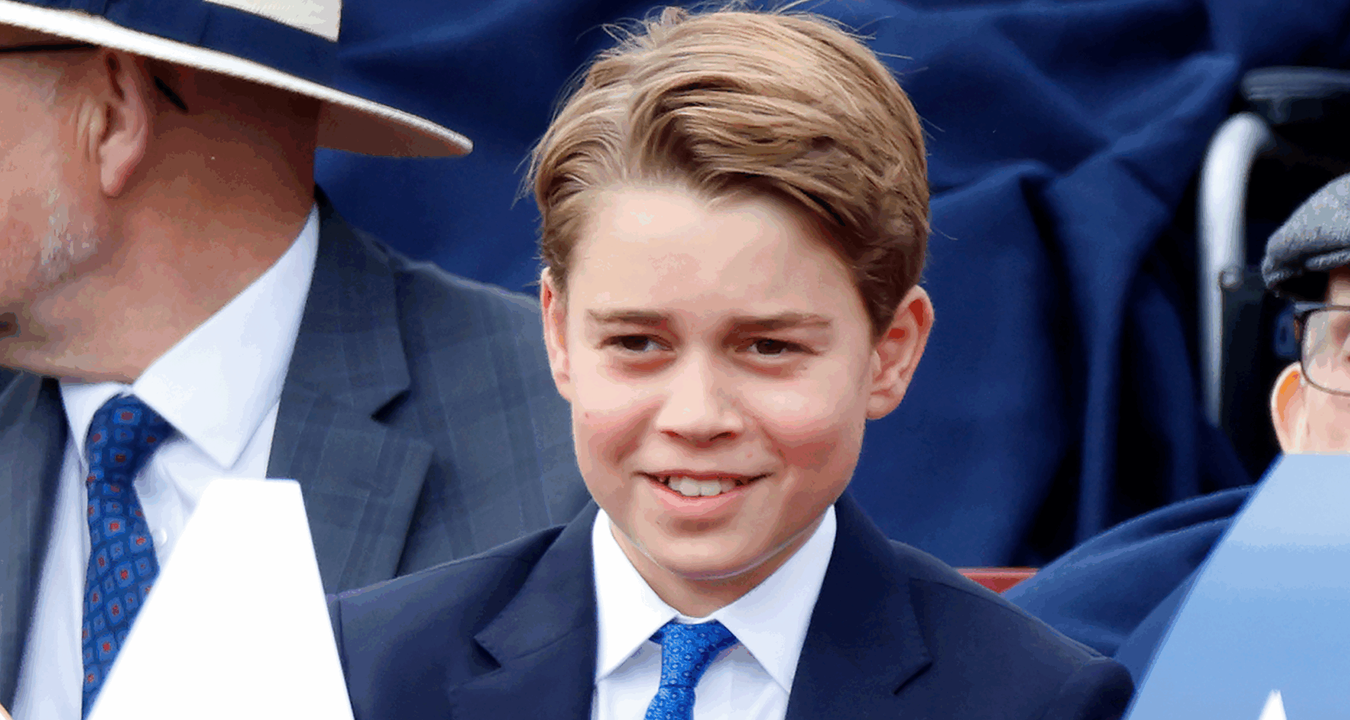 Prince George smiling in a blue suit and tie