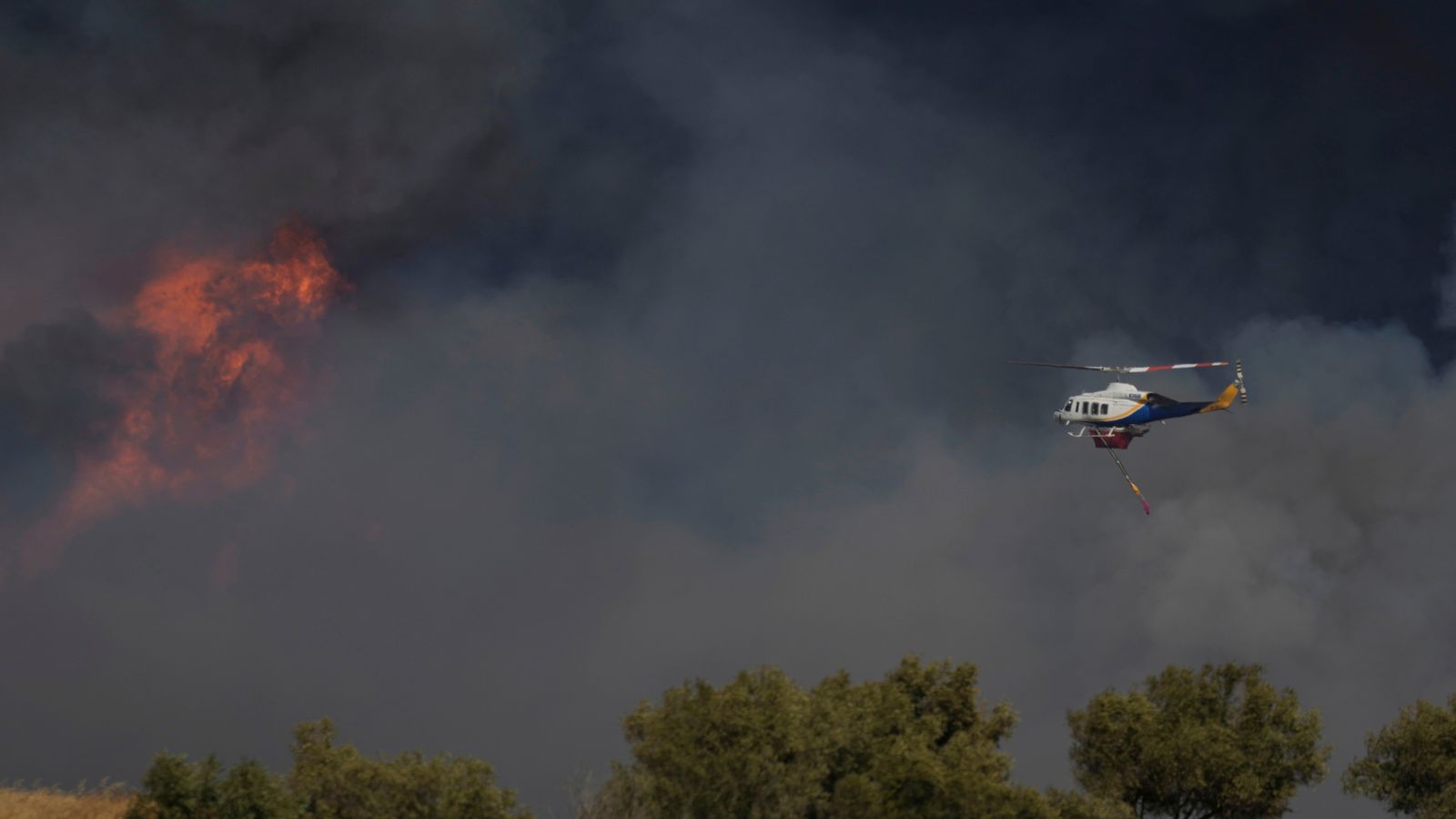 A helicopter flies through smoke in Keratea on the outskirts of Athens. Pic: AP