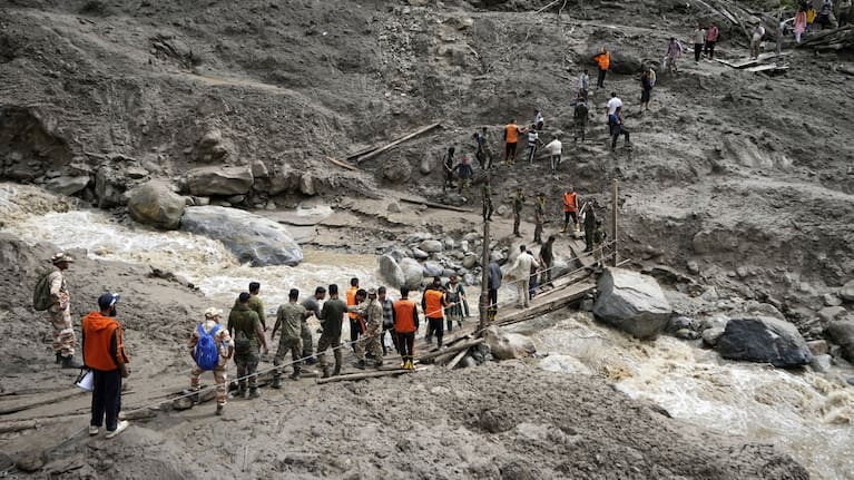 Stranded pilgrims are helped across a water channel using a makeshift bridge a day after flash floods in Chositi village, Kishtwar district, Indian-controlled Kashmir, August 15, 2025.
