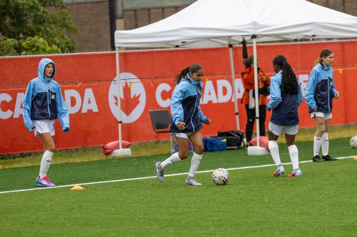 Soccer players in rain jackets under the rain.