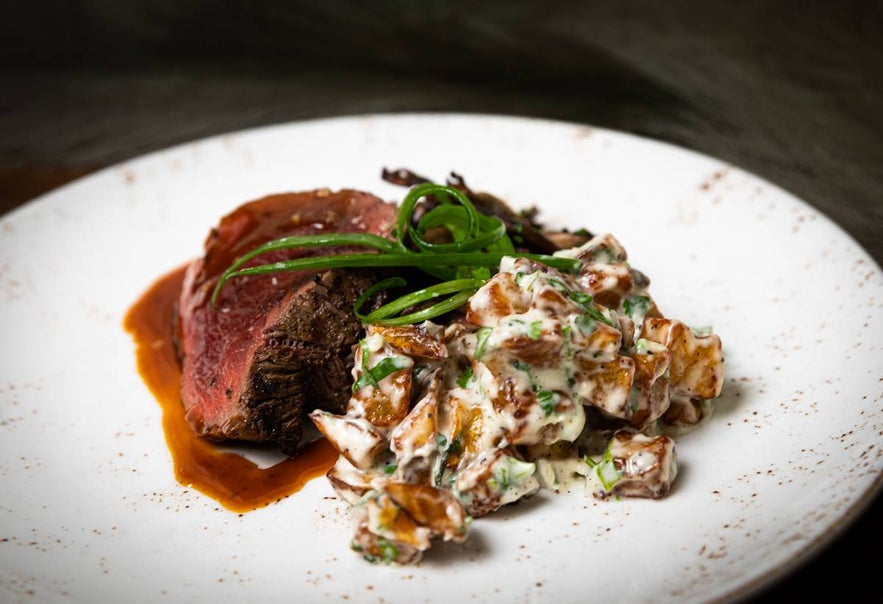 Beef tenderloin with creamy risotto and fresh green garnish at Tryggvaskali in Selfoss, Iceland.