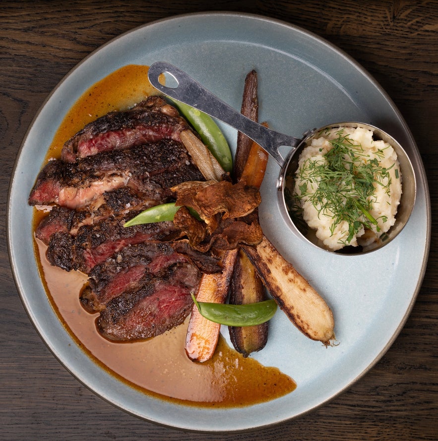 Reverse sear bone-in ribeye with roasted vegetables and a side of mashed potatoes at Lilly & Julia’s – Viking BBQ.