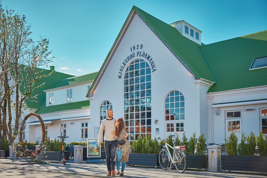 A couple strolling past the Old Dairy Food Hall in Selfoss, Iceland.