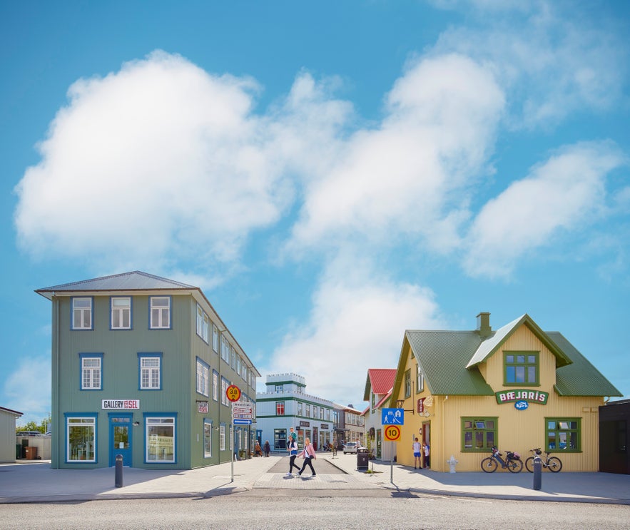 Colorful buildings, pedestrians, and bikes under a bright blue summer sky in Selfoss, Iceland.