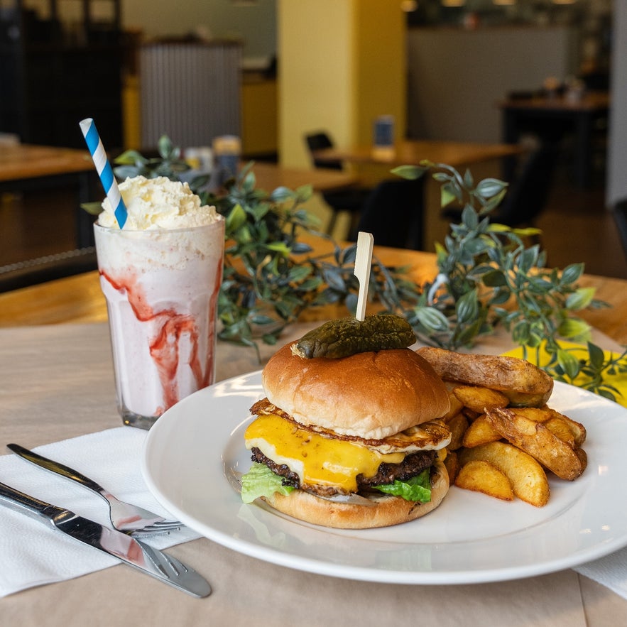Delicious cheeseburger with fries, egg, and a refreshing strawberry milkshake, served at Byrja in Selfoss.