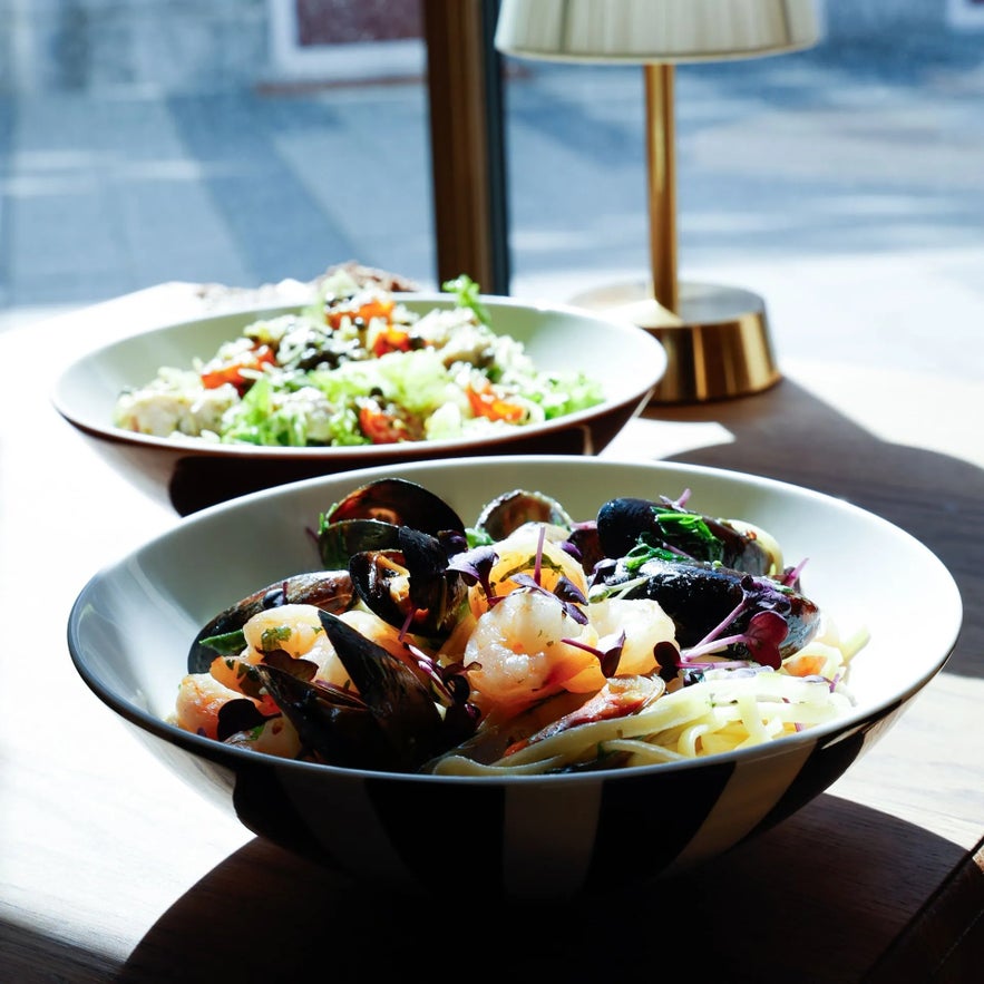 Fresh seafood pasta with mussels, shrimp, and herbs, alongside a vibrant garden salad, served at Froken Selfoss.