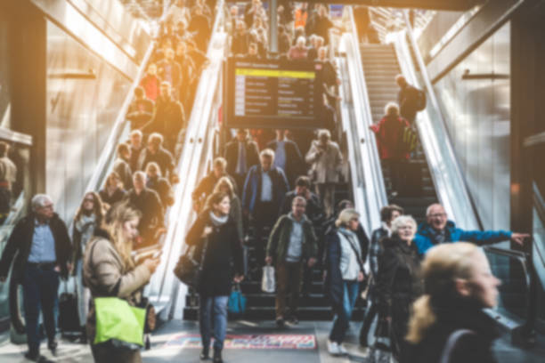 A busy train station with people walking and using escalators under a large departure board.