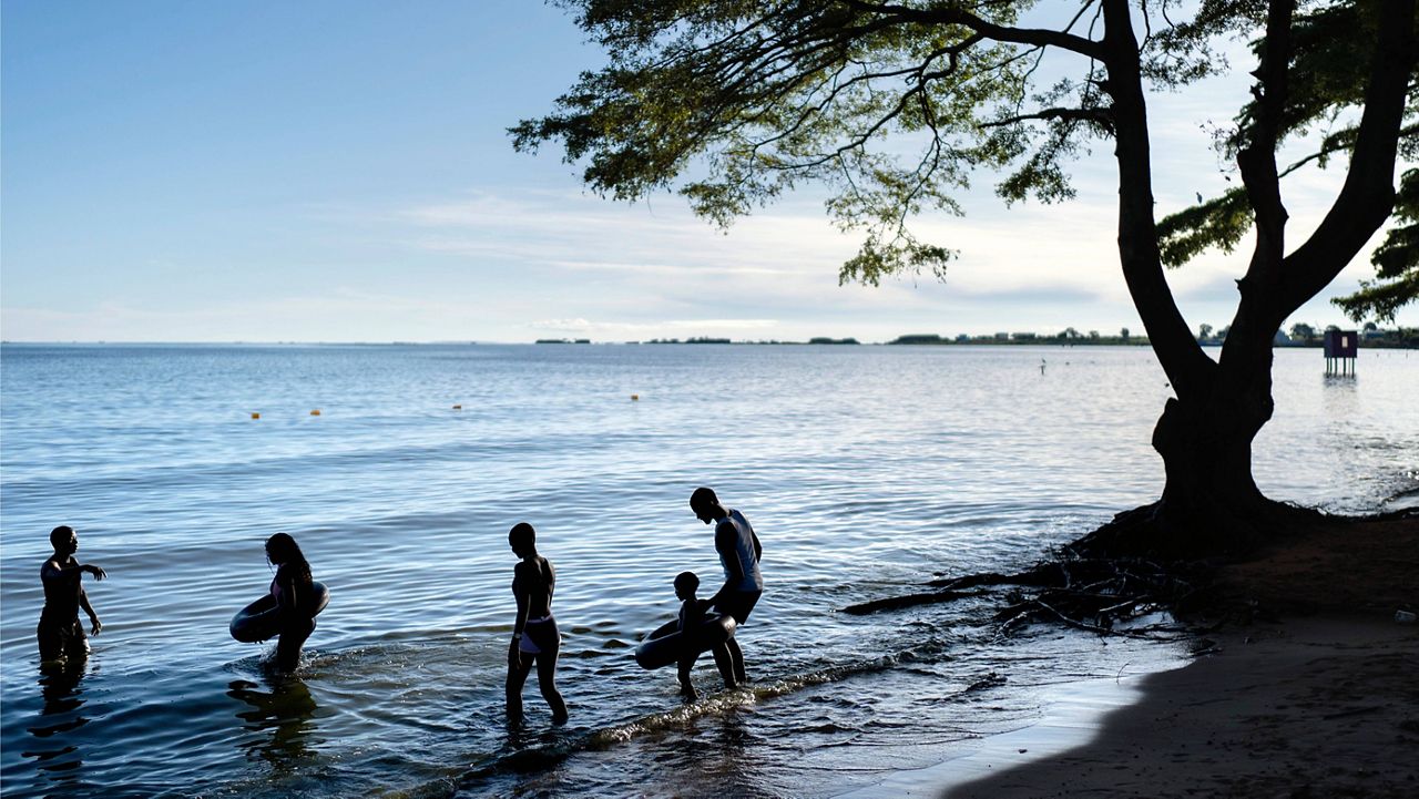 People wade into the waters of Lake Victoria, the world's second-largest freshwater lake, Nov. 25, 2024, in Entebbe, Uganda. (AP Photo/David Goldman, File)
