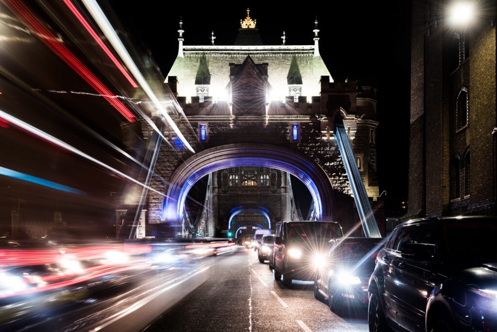 Stationary traffic and light trails on a city street at night, Tower Bridge, London.