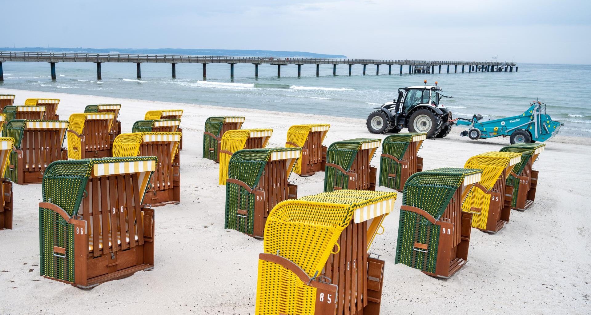 Strandkörbe stehen vor der Seebrücke auf der Insel Rügen am Ostseestand.