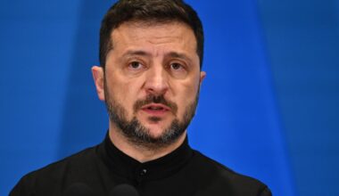 Wolodymyr Selenskyj steht auf einem Podium vor blauem Hintergrund.