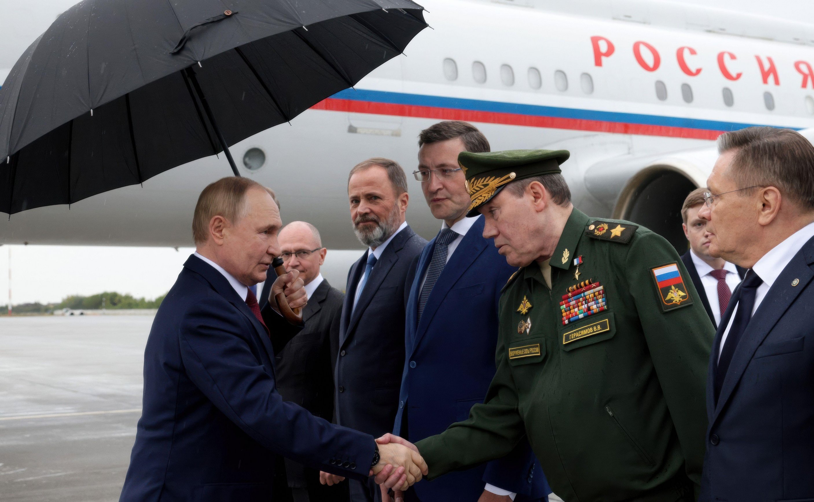 Vladimir Putin shaking hands with Valery Gerasimov at an airport.