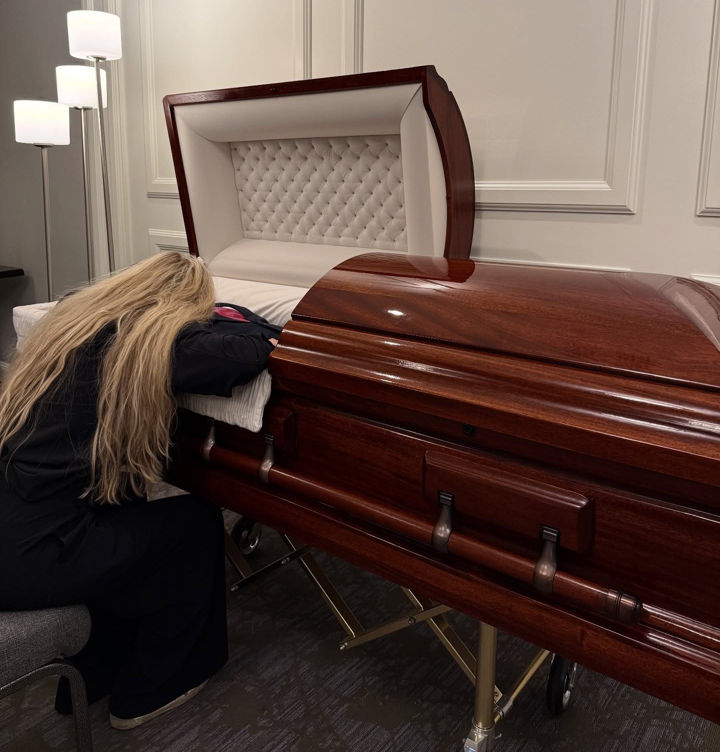Woman grieving at her husband's open casket.