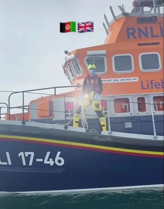 A video still showing an Afghan migrant, DG Usama, on an RNLI cutter boat, with the flags of Afghanistan and the UK superimposed.