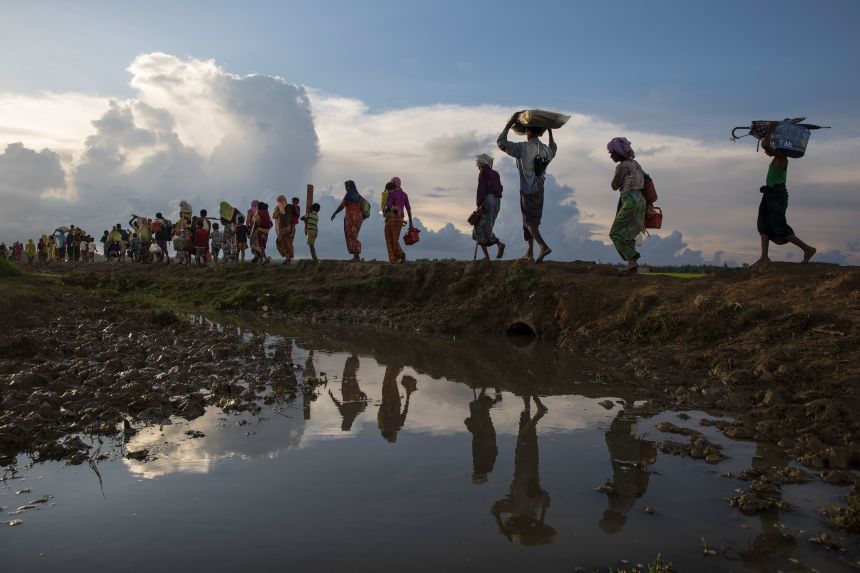 Thousands of Rohingya refugees fleeing from Myanmar walk along a muddy rice field after crossing the border in Cox's Bazar, Bangladesh, on October 9, 2017.