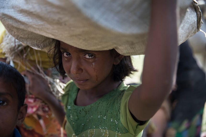 A Rohingya girl cries as she and refugees fleeing from Myanmar cross a stream on a muddy rice field near Cox's Bazar, Bangladesh, on October 16, 2017.