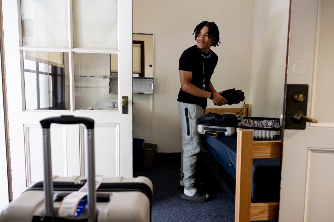 A student unpacks their suitcase inside of their dorm room.