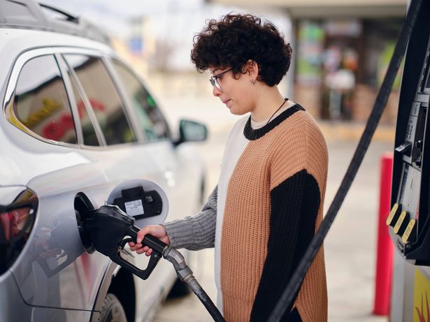 A young woman fueling up her car at a convenience store.