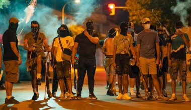 Protesters wearing masks and balaclavas hold chains, sticks and baseball bats during the fourth night of riots on July 14, 2025 in Torrepacheco, in the province of Murcia, Spain