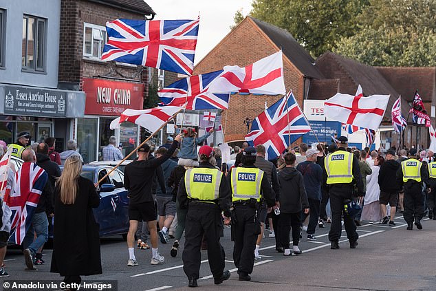 Demonstrators wave English and British flags as they protest outside The Bell Hotel