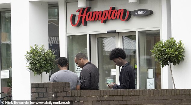 Men are seen milling around outside the Hampton by Hilton when the Mail visited