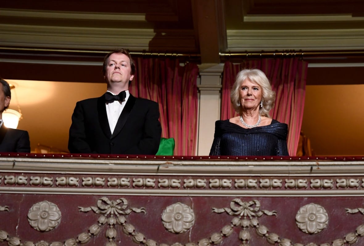 Two people stand in an elaborate balcony of an auditorium.