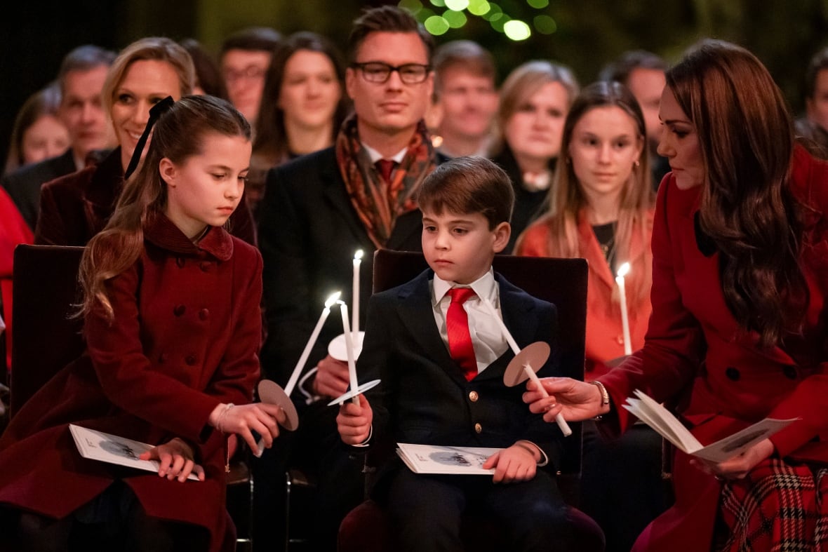 Two children and an adult light candles with one another during a Christmas concert.