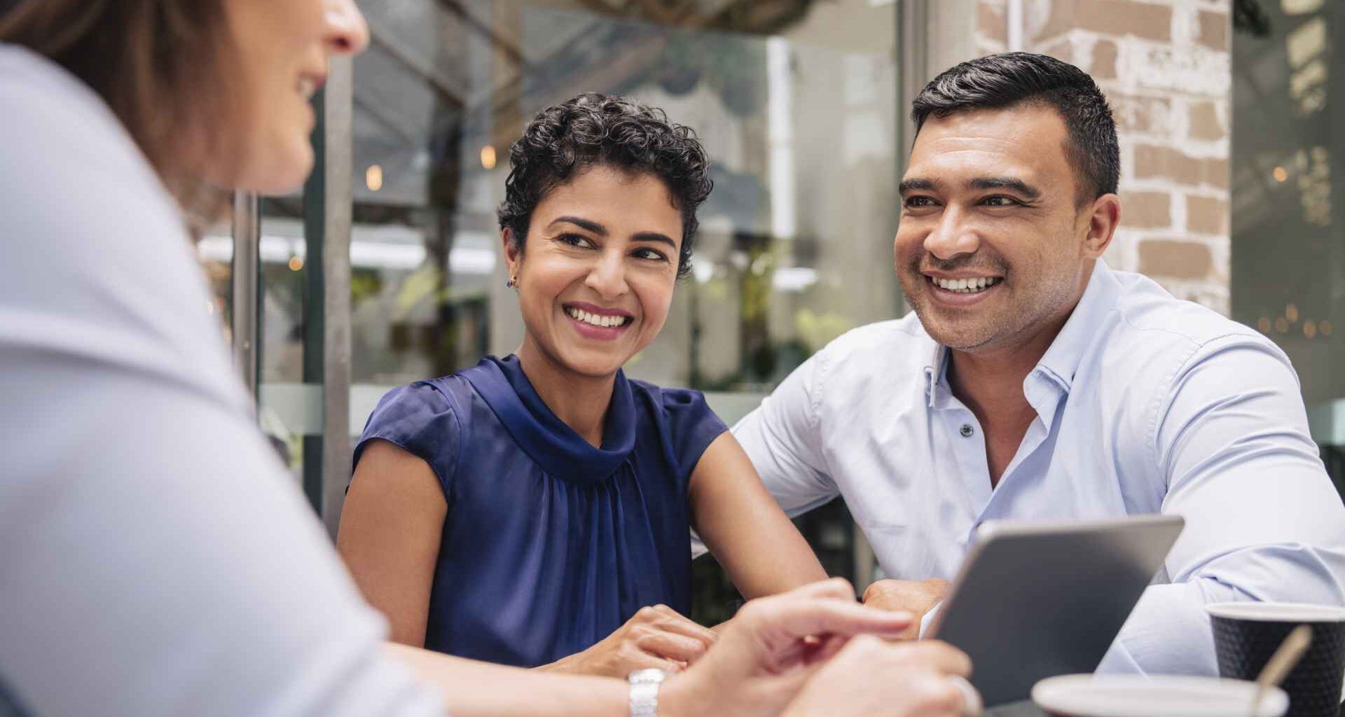 A couple smiles and looks happy during a meeting with their adviser.