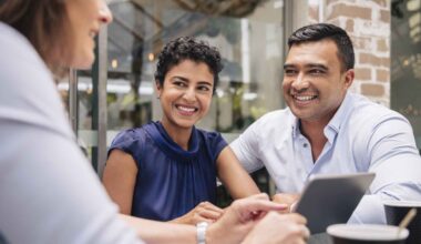 A couple smiles and looks happy during a meeting with their adviser.
