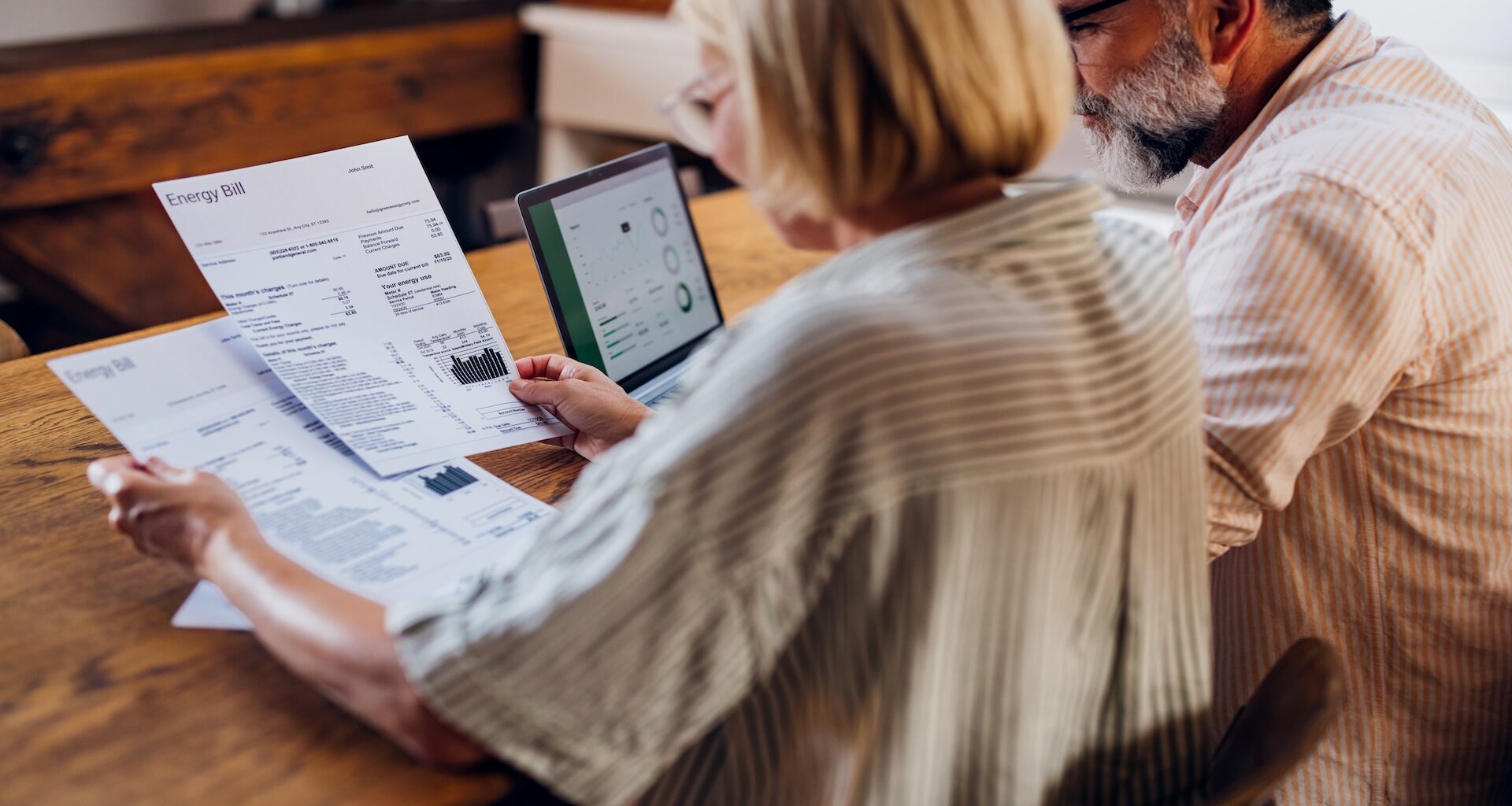 Senior couple carefully reviewing their household energy bill together on a laptop at home.