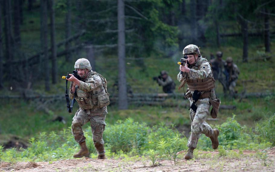 Two soldiers run with rifles raised during a training exercise.