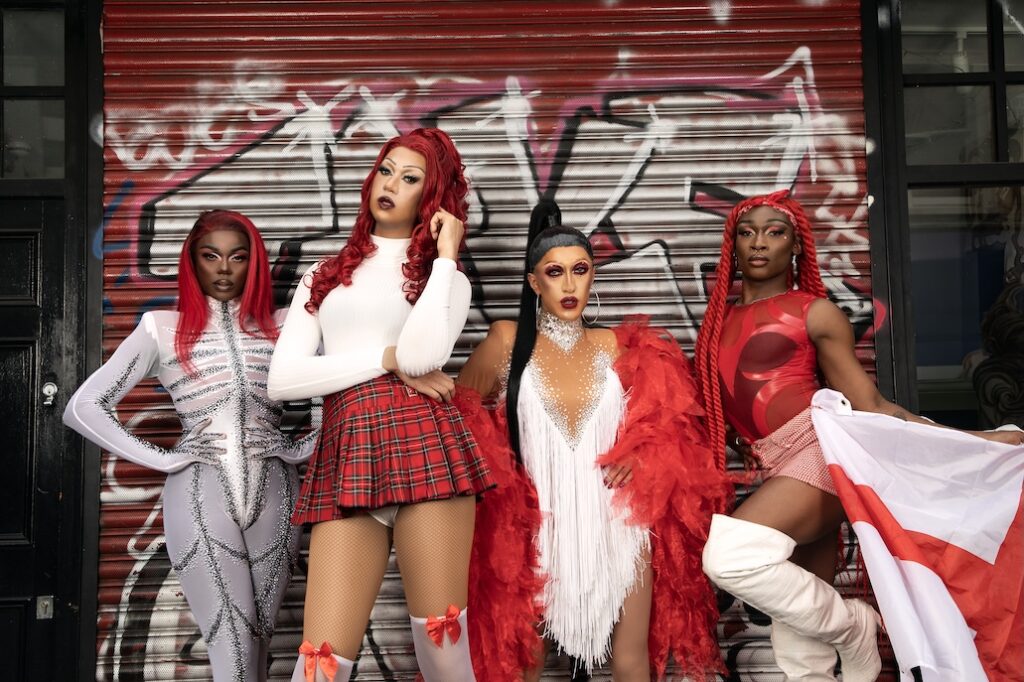 Drag Queens dressed in red and white against a graffiti wall 