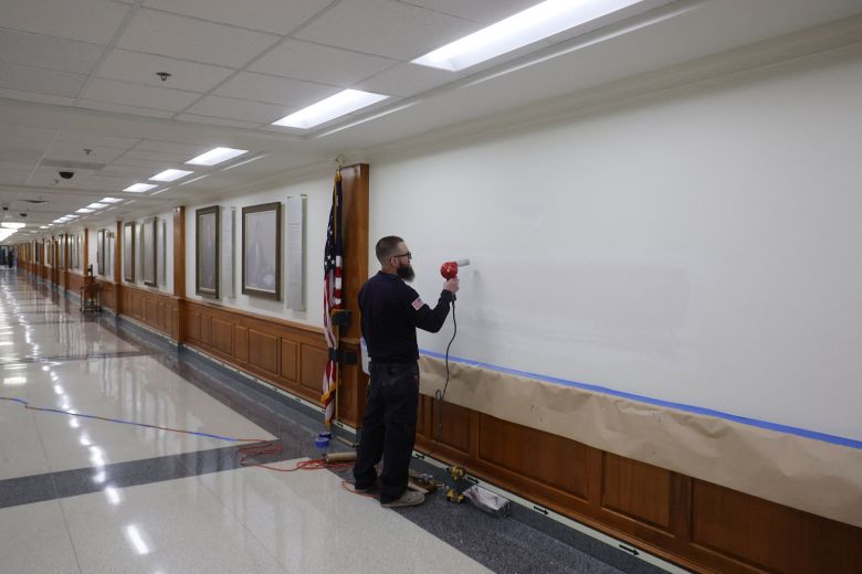 A worker prepares a wall for new signs on the corridor outside Deputy Secretary of Defense Steve Feinberg's office, after President Donald Trump ordered the Department of Defense to be renamed as the 