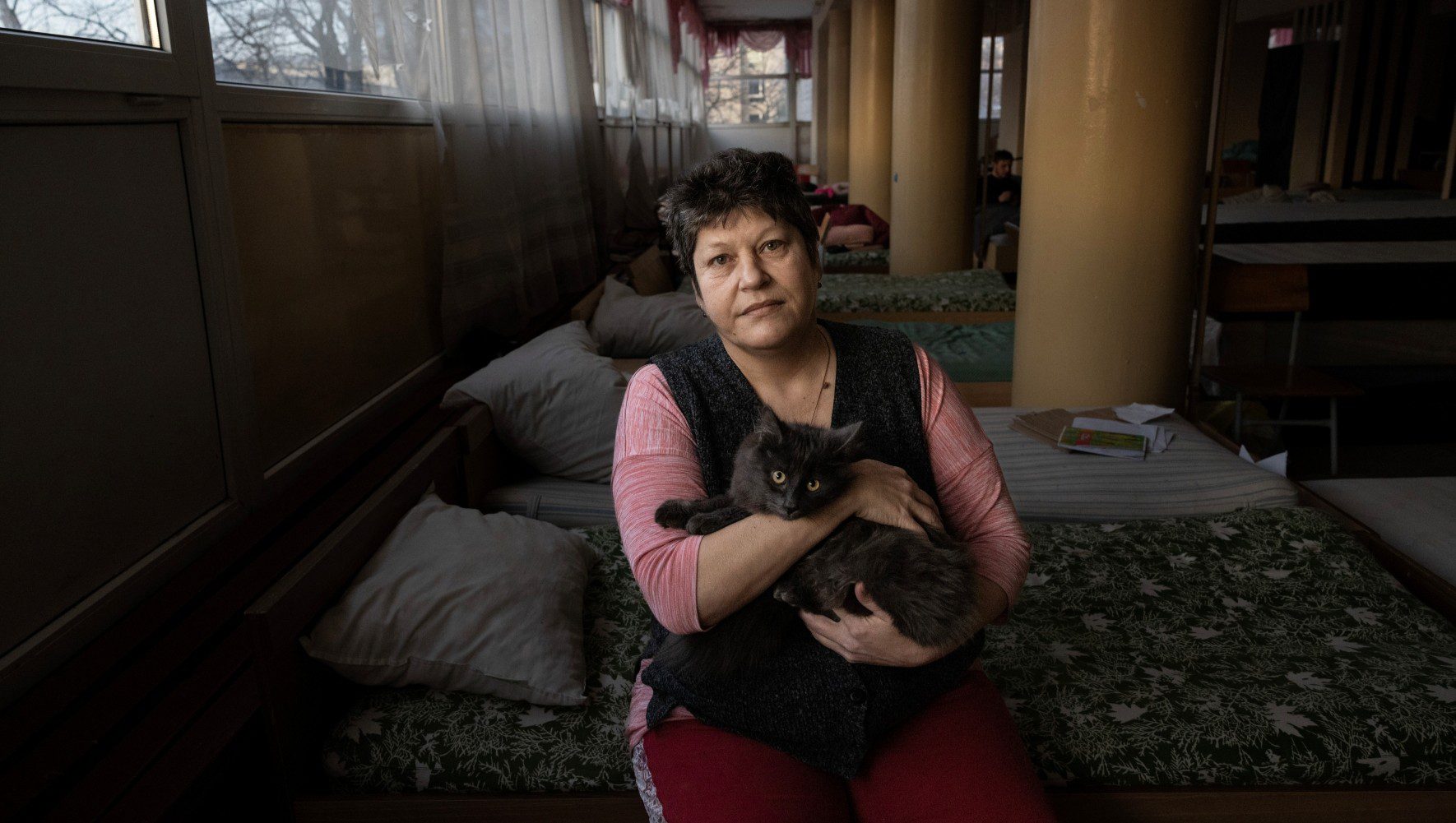 Anna and her cat Vinya inside the university shelter where they have been living since March 13, 2022 in Lviv, Ukraine on February 12, 2023. Anna's small village in the Donetsk district was destroyed, forcing her to flee and seek refuge. (Paula Bronstein for HIAS).