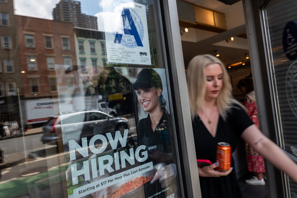 A Chipotle Mexican Grill window in New York City with a "Now Hiring" sign and an "A" grade inspection report.