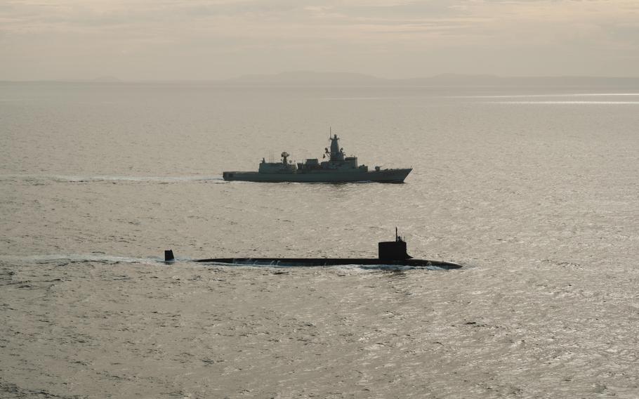 A submarine and a frigate sailing side by side in the ocean.
