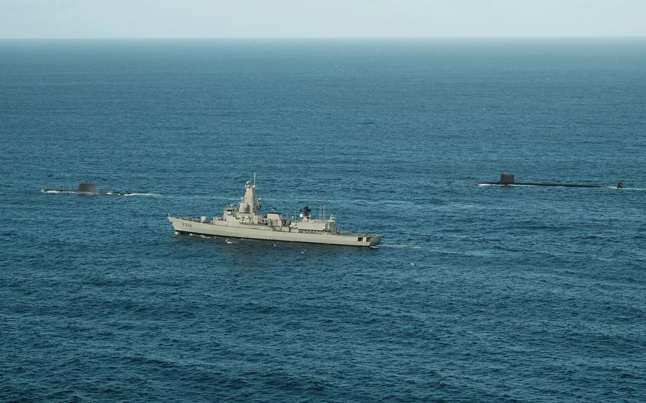 A frigate sailing by submarines.