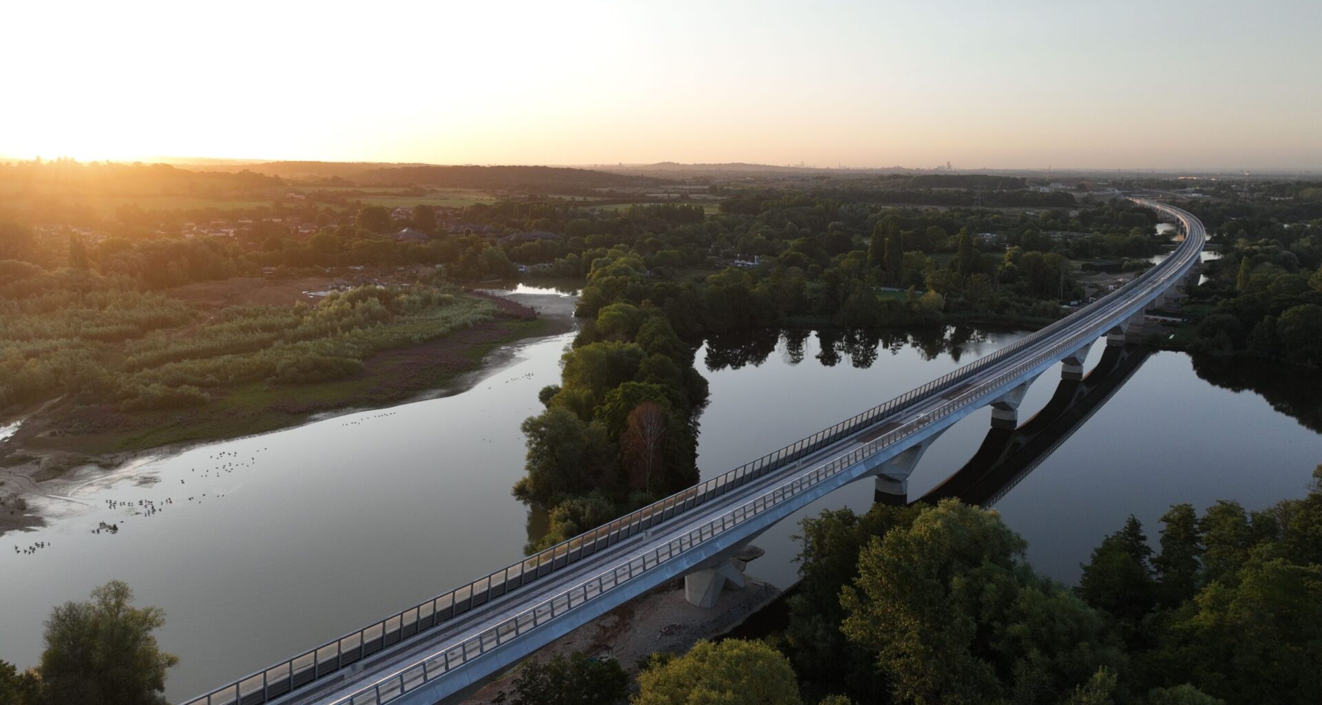 A rail bridge over water during sunset