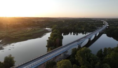 A rail bridge over water during sunset