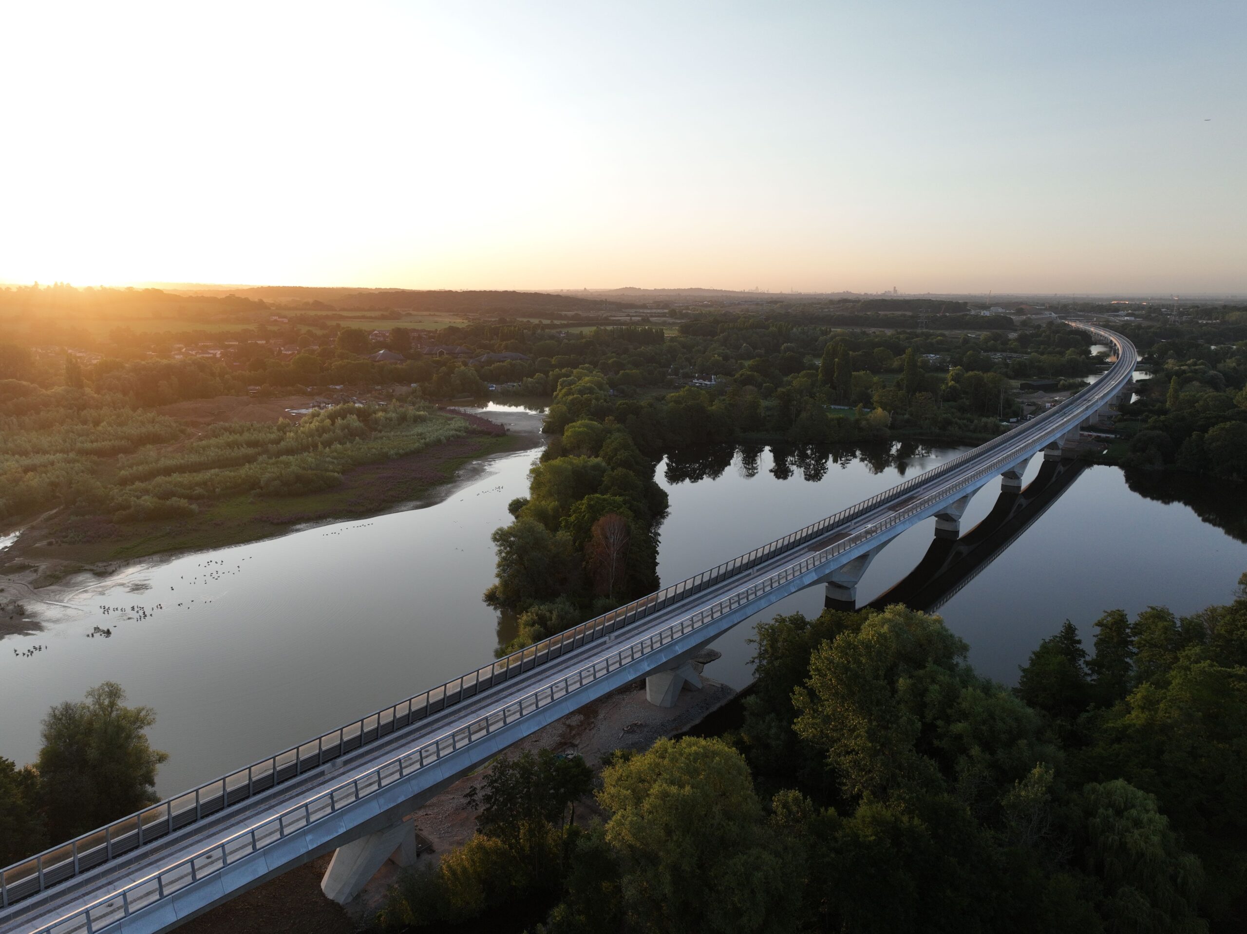 A rail bridge over water during sunset