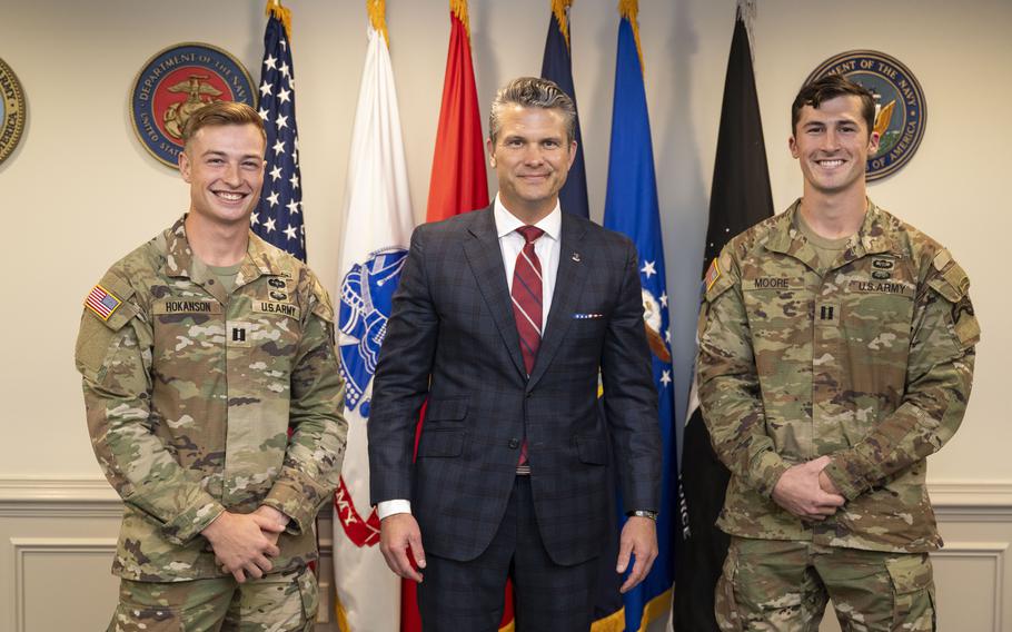Pete Hegseth poses for a photo with two soldiers.