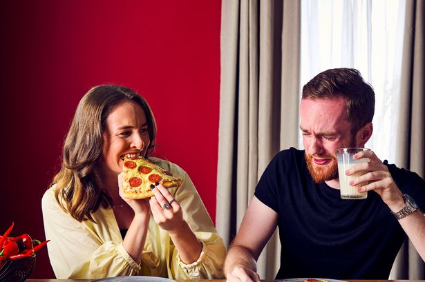 Man and woman eating spicy pizza - the woman is fine but the man has a red face