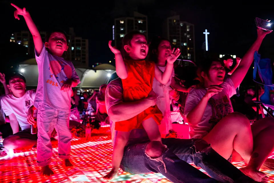 Lee Yeon-woo, 5, and sisters Kim Seo-a, 4, and Kim A-rin, 5, cheer as they watch the drone show with their parents. - (Jintak Han/The Washington Post)