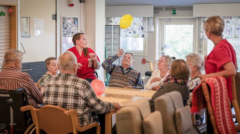 Photo shows a group of older people sitting around a table.