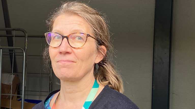 Nainen katsoo kameraan jätekatoksessa.