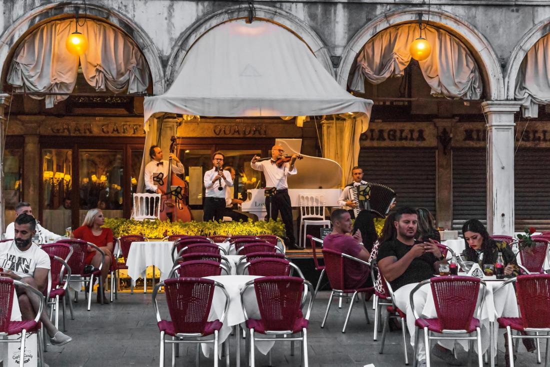VENICE, ITALY - SEPTEMBER 9, 2018: Unidentified people relax in one of the cafes to the romantic liv.