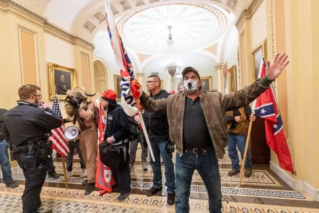 In this Jan. 6, 2021, file photo, supporters of President Donald Trump are confronted by U.S. Capitol Police officers outside the Senate Chamber inside the Capitol in Washington. Both within and outside the walls of the Capitol, banners and symbols of white supremacy and anti-government extremism were displayed as an insurrectionist mob swarmed the U.S. Capitol. 